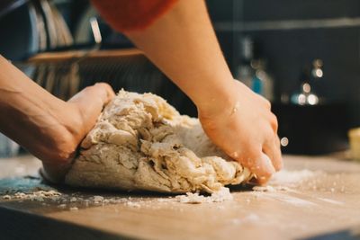 Hands shaping sourdough on a floured wooden surface