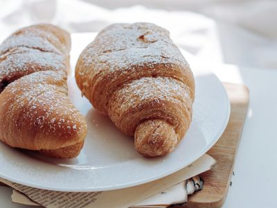 A golden almond croissant dusted with powdered sugar and flaked almonds