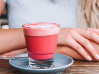 An iced rose latte in a tall glass with a soft pink hue