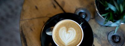 Close-up of a freshly baked almond croissant and a latte on a wooden table